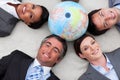 Business people lying on the floor around a globe Royalty Free Stock Photo