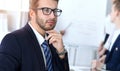 Business people at meeting in office. Focus at cheerful smiling bearded man wearing glasses. Conference, corporate