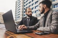 business people meets outdoors. Two men are using a laptop. Working break. Team and business support. Collaboration and Royalty Free Stock Photo