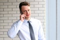 Business, people and office concept - happy young businessman calling on smartphone over office near with window Royalty Free Stock Photo