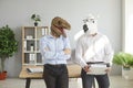 Two office workers in funny dinosaur and horse masks standing by desk and talking Royalty Free Stock Photo