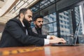 Business people outdoor meeting. A group of business people meet outdoors. Two men are using a laptop. Working break Royalty Free Stock Photo