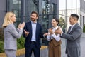 Business people outside office building applauding and congratulating colleague boss with promotion and good results Royalty Free Stock Photo