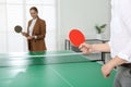 Business people playing ping pong in office, focus on tennis racket. Space for text Royalty Free Stock Photo