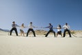 Business People Playing Tug Of War In The Desert Royalty Free Stock Photo