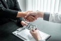 Business people shaking hands with money in hands from their partner to give success the deal contract in a corruption scam, Royalty Free Stock Photo