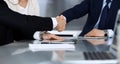 Business people shaking hands while working together at the glass desk in modern office. Unknown businessman, male entrepreneur wi