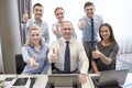 Business people showing thumbs up in office