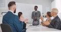 Business people sitting in office applauding to african-american male colleague after successful presentation Royalty Free Stock Photo