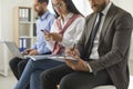 Business people sitting in office, writing on clipboards and using laptops and mobile phones Royalty Free Stock Photo