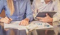 View of business people, sitting at the table and pointing handles on the chart and on tablet