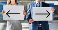 Business people standing while holding white Left and Right arrow placard in arrival area at airport