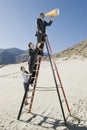 Business People on Stepladder Using Megaphone in Desert Royalty Free Stock Photo
