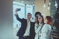 Group of cheerful colleagues taking selfie and gesturing while standing in the modern office. Royalty Free Stock Photo