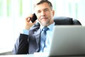 Business, people and technology concept - happy smiling businessman with laptop computer office