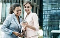 Business, people, tehnology and lifestyle concept: Two business women with mobiles near office