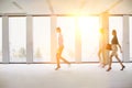 Business people walking in office hall with yellow lens flare in background Royalty Free Stock Photo