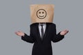Business person anonymous hiding his head behind happy smile emoticon on gray background Royalty Free Stock Photo