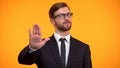 Business person doing stop gesture, rejecting to overwork, orange background