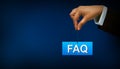 Business person holding FAQ sign on blue background