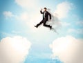 Business person jumping over clouds in the sky