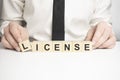Business person presses his finger on the wooden cubes with the word license. Copyright protection law license property rights Royalty Free Stock Photo