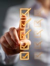 Business person selecting completed tasks on a virtual checklist with illuminated glowing orange checkmarks for productivity and Royalty Free Stock Photo