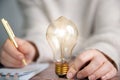 Business person writing notes,ideas,creative brainstorming with shining lightbulb