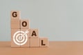 Business or personal achievement goal and objective target concept. GOAL word and white dartboard icon on step of wooden cube