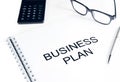 Business plan words near calculator, glasses and pen, business concept