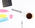 Business plan words near highlighters, calculator and cup of coffee, business concept Royalty Free Stock Photo
