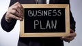 Business plan written on blackboard, male hands holding sign, strategy, goals Royalty Free Stock Photo