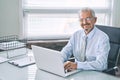 Business portrait of an elderly man. An aged man working on a laptop, looking at the camera and smiling. Work on removal Royalty Free Stock Photo