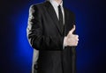 Business and the presentation of the theme: man in a black suit showing hand gestures on a dark blue background in studio isolated Royalty Free Stock Photo