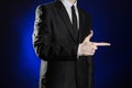 Business and the presentation of the theme: man in a black suit showing hand gestures on a dark blue background in studio isolated Royalty Free Stock Photo