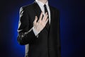 Business and the presentation of the theme: man in a black suit showing hand gestures on a dark blue background in studio isolated Royalty Free Stock Photo