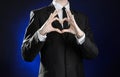 Business and the presentation of the theme: man in a black suit showing hand gestures on a dark blue background in studio isolated Royalty Free Stock Photo