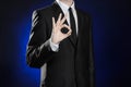 Business and the presentation of the theme: man in a black suit showing hand gestures on a dark blue background in studio isolated Royalty Free Stock Photo