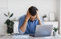 Business Problems. Desperate Millennial Businessman Sitting At Workplace In Office, Touching Head