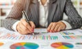 A business professional analyzes graphs and charts, using a pen to highlight key data points on paper