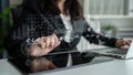 Business professional analyzing digital graphs and charts on a tablet while working on a laptop in a modern office Royalty Free Stock Photo