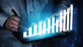 Business professional analyzing growth data on a digital tablet with a vibrant graph visualization showing positive Royalty Free Stock Photo