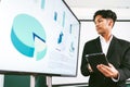 Business professional presenting financial data on a digital screen with tablet in hand, highlighting analytic, corporate strategy Royalty Free Stock Photo