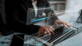 Business professional working on a laptop with digital interface displaying loading progress and analytical data in a Royalty Free Stock Photo