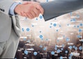 Business professionals shaking hands against networking icons in background Royalty Free Stock Photo