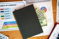 Still Life of Dollar Bank Notes in Notebook over Project plan and report Representing Dishonesty in the Economy Royalty Free Stock Photo