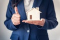 Business Property Selling and Estate Investment Concept, Close-Up Portrait of Business Woman in Suit Showing House Model With