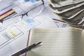 Business research. Notebook with fountain pen, dollar banknotes, glasses on reports and paper with figures, charts. Royalty Free Stock Photo