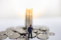 Business, Risk Management, Money and Planning Concept. Close up of businessman miniature figure standing and looking to pile and