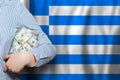 Business, saving, finance, politics and corruption in Greece concept. US dollars cash money in hand on Greek flag background